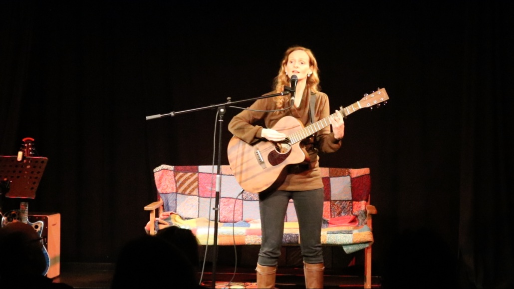 Kira Ludlow singt und spielt Gitarre bei einem Konzert